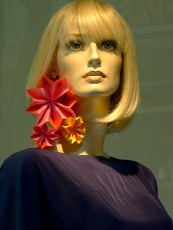 Blond doll face with red flower with a green backgroundの写真素材