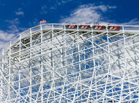 Thrill seekers rider a rollercoaster as it climbs a hill の写真素材