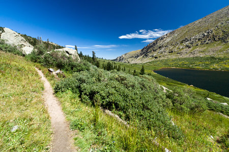 Hiking trail climbs upward through a mountain lake landscape in Coloradoの写真素材