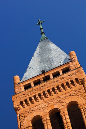 Cross on a church steeple isolated against a blue sky backgroundの写真素材