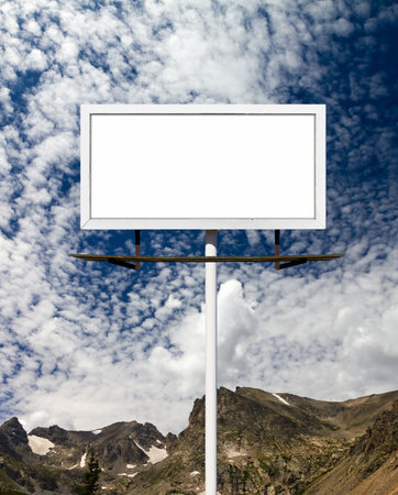 Blank billboard sign in the blue sky above the mountainsの写真素材