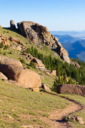 Dirt hiking trail winds through the Colorado Rocky Mountains on a clear blue sky dayの写真素材