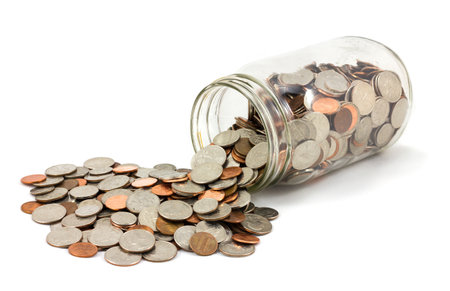 Jar of US coins spilled on a whiteの写真素材