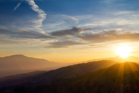 Colorful sunset rays over distant mountains in Joushua Tree National Park, Californiaの写真素材