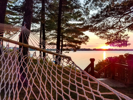 Scenic landscape view from a hammock hanging in the trees near a lake with the colorful summer sunset in the backgroundの写真素材
