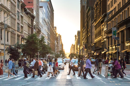 NEW YORK CITY - CIRCA 2017: Busy crowds of people cross the intersection of 5th Avenue and 23rd Street in Manhattan, New York City with the colorful setting sun in the background on June 3rd, 2017.のeditorial素材