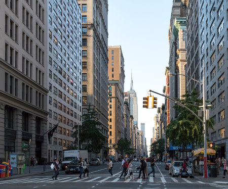 NEW YORK CITY - CIRCA 2017: People walk across a busy intersection on Fifth Avenue with the Empire State Building in the background skyline of Manhattan, New York City in 2017.のeditorial素材