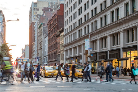 Fast paced street scene with people walking across a busy intersection on Broadway in Manhattan New...