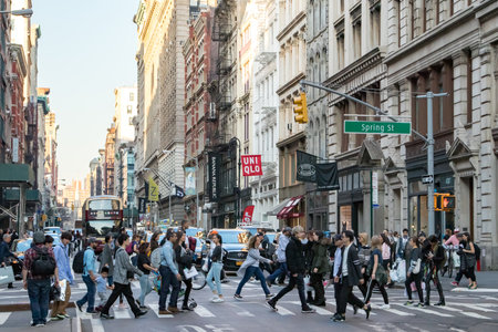 NEW YORK CITY, CIRCA 2018: Busy crowds of people walk across the intersection of Broadway and Spring Street in the SoHo neighborhood of Manhattan, NYC.のeditorial素材