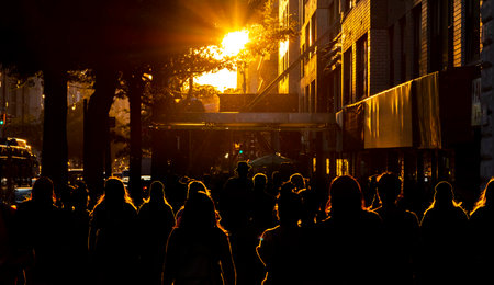Silhouettes of people are illuminated by the bright light of sunset on the sidewalks of New York City NYCの写真素材