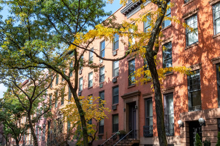 Tree lined street with colorful fall trees and historic buildings in the Chelsea neighborhood of...