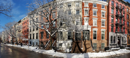 Sun shines on a snow covered block of colorful buildings along 10th Street in the East Village neighborhood of New York City NYCのeditorial素材