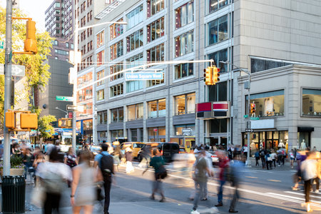 Crowds of people walking across the busy intersection on 14th Street at Union Square Park in New York City NYC past the cars and buildingsの写真素材