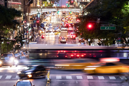 Buses and taxis driving through a busy intersection 42nd Street through Midtown Manhattan in New York City at nightの写真素材