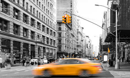 Yellow taxi driving in black and white street scene on Fifth Avenue with busy crowds of people in Manhattan New York City NYCの写真素材