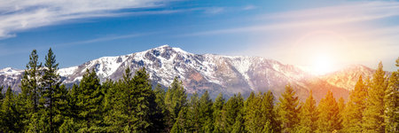 Panoramic landscape scene with sunlight shining behind the snow capped mountains in Lake Tahoe Californiaの写真素材