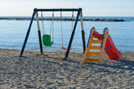 swing and slide, children's games on the beach, facing the sea with cliffsの写真素材