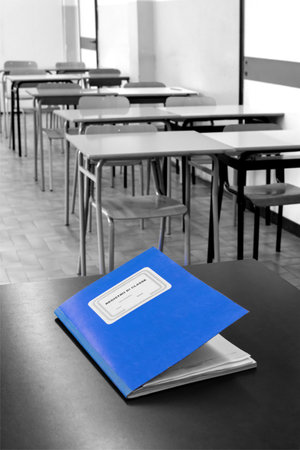class register closed on the desk, inside a class of a high school, in the background the students' desks. Translation: "class register"の写真素材