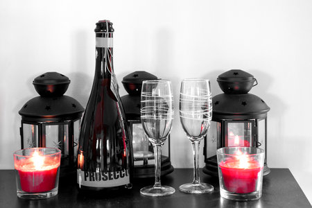 romantic atmosphere with bottle of prosecco, wine glasses and lighted candlesの写真素材