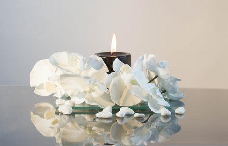 Black candle with flame and white liliesの写真素材