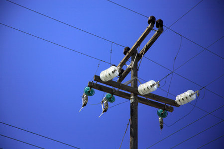 Polw with power and phone lines and junctions against a blue sky