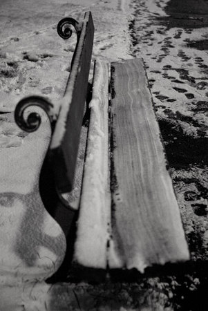 Bench covered in snow and footprintsの写真素材