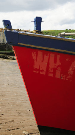 The red hull of a fishing boat moored on Staithes beachの写真素材
