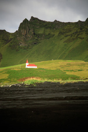 White church on the hill from the black volcanic beach Icelandの写真素材
