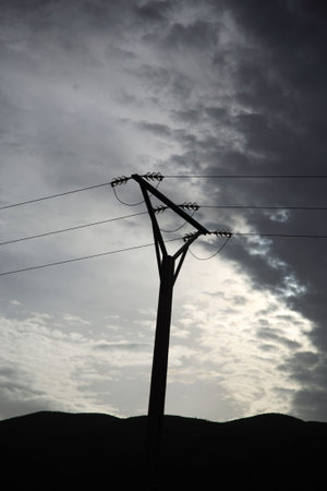 Powerlines silhouetted against a dramatic skyの写真素材