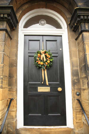 Oranges and cinnamon Christmas wreath on a black doorの写真素材