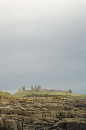 Dunstanburgh castle against a dramatic sky Northumberland Englandの写真素材