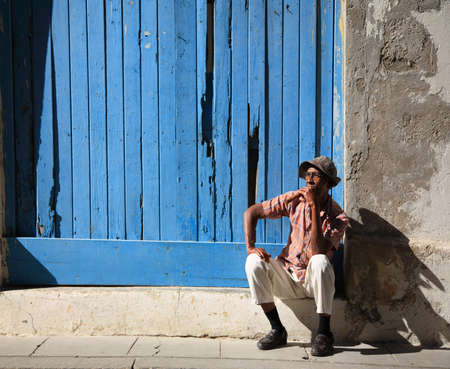 Cuban man and his cigar sat on a step in the streets of Havana in Cuba 10 January 2009のeditorial素材