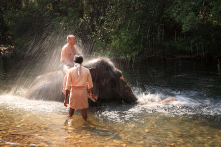 Tourist being sprayed by an elephant playing in the river, Goa India 17 January 2008のeditorial素材