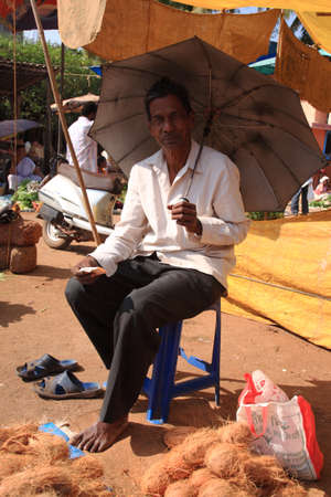Man sheltering from the sun under an umbrella in Goa, India 17 January 2008のeditorial素材