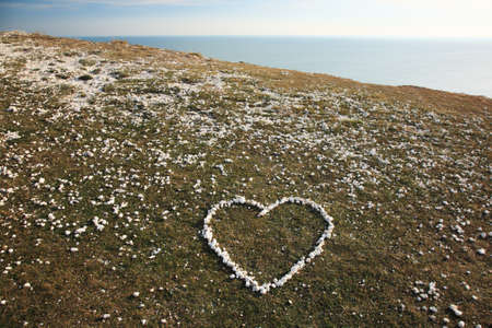Love heart made from pebbles on the cliff topの写真素材