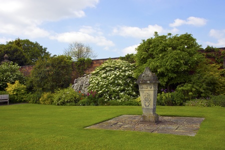 Formal English walled garden with stone ornament and freshly mawed lawn 