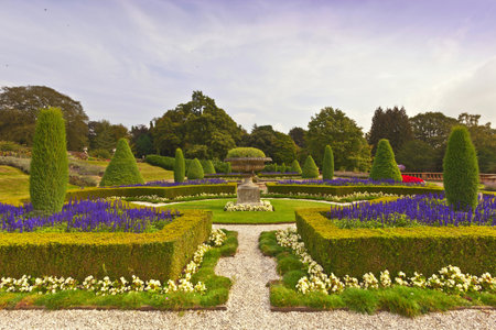 Landscaped garden with topiary and an old stone vase at an historic English estateのeditorial素材