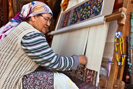 SIDE, TURKEY - MARCH 9, 2015: Unidentified female weaver knotting a handmade carpet at the shopping area in the town of Side.のeditorial素材
