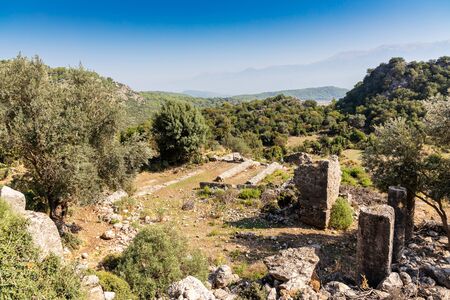 Ruins of temple at ancient city of Pinara in Turkey with heart shaped column in foreground.の写真素材