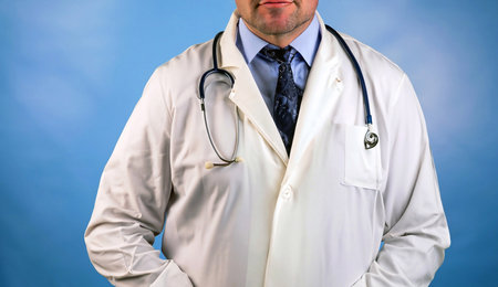 Doctor man sitting at the desk at his working place and smiling at camera. Perfect medical service in clinic. Happy future of medicine and healthcare. happy doctor looking at cameraの写真素材