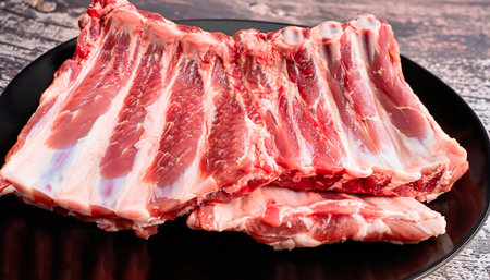 Raw ribs with rosemary and spices on a cutting board. On a black background. High quality photoの写真素材