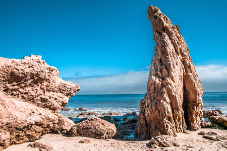 Large rocks on a beach with a blue cloudy skyの写真素材