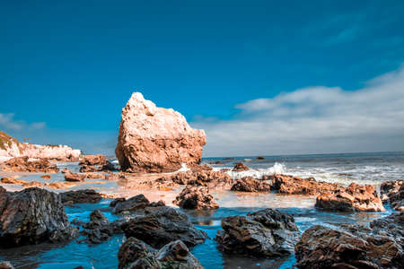 Rocky beach with blue cloudy sky near a cliffの写真素材