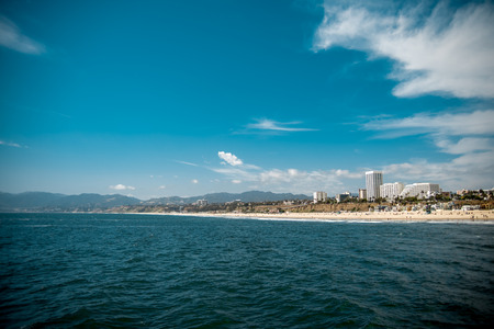 Beach with buildings near mountains with a blue cloudy skyの写真素材