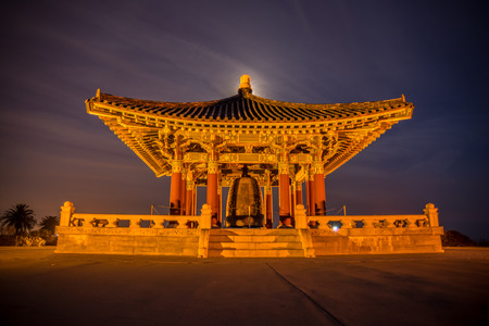 Korean Friendship Bell in San Pedro with warm lighting and a purple sky with the moon behind itの写真素材