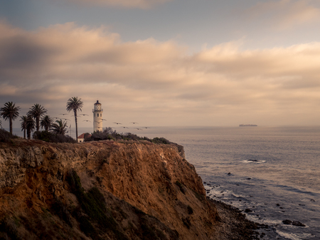 Lighthouse on a cliff during sunsetの写真素材