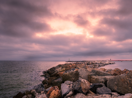 Breakwater under a cloudy red skyの写真素材
