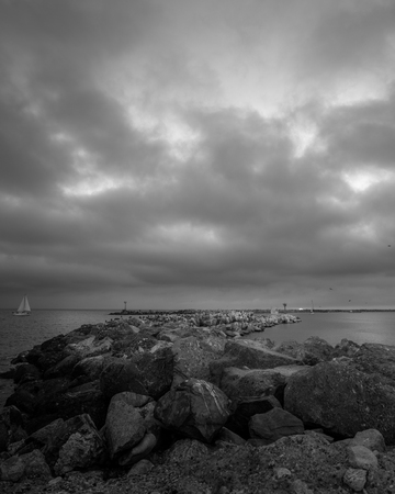 Black and white breakwater under cloudy skyの写真素材