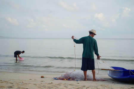 Fisherman is prepare the net for his work on the beachの写真素材