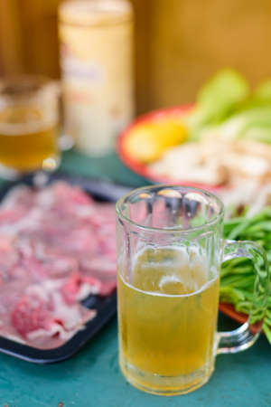 Cool beer in the glass with pork, vegetables and raw materials for cooking.の写真素材